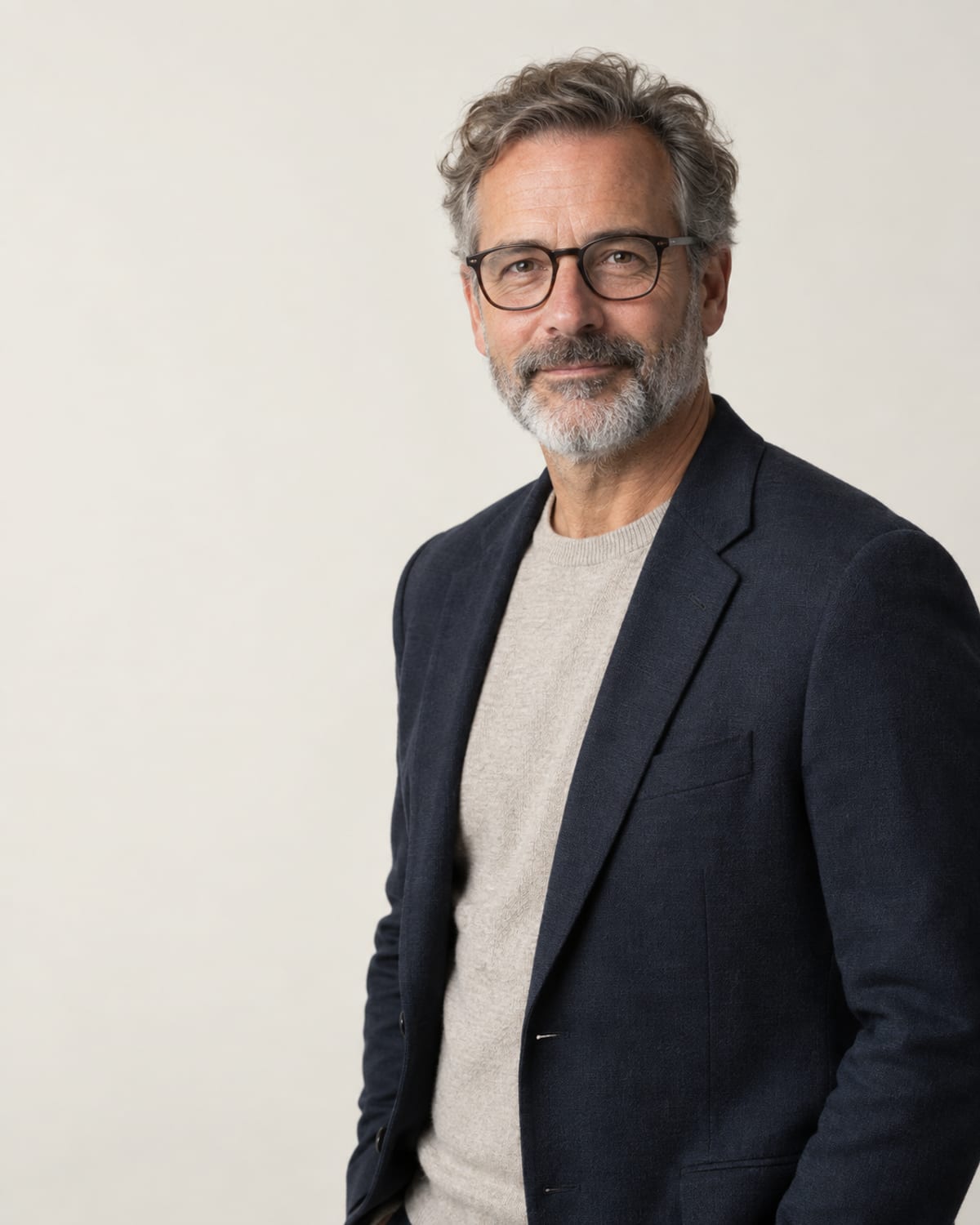 AI-generated layout placeholder portrait of a man with a greying beard and glasses; replace before launch.
